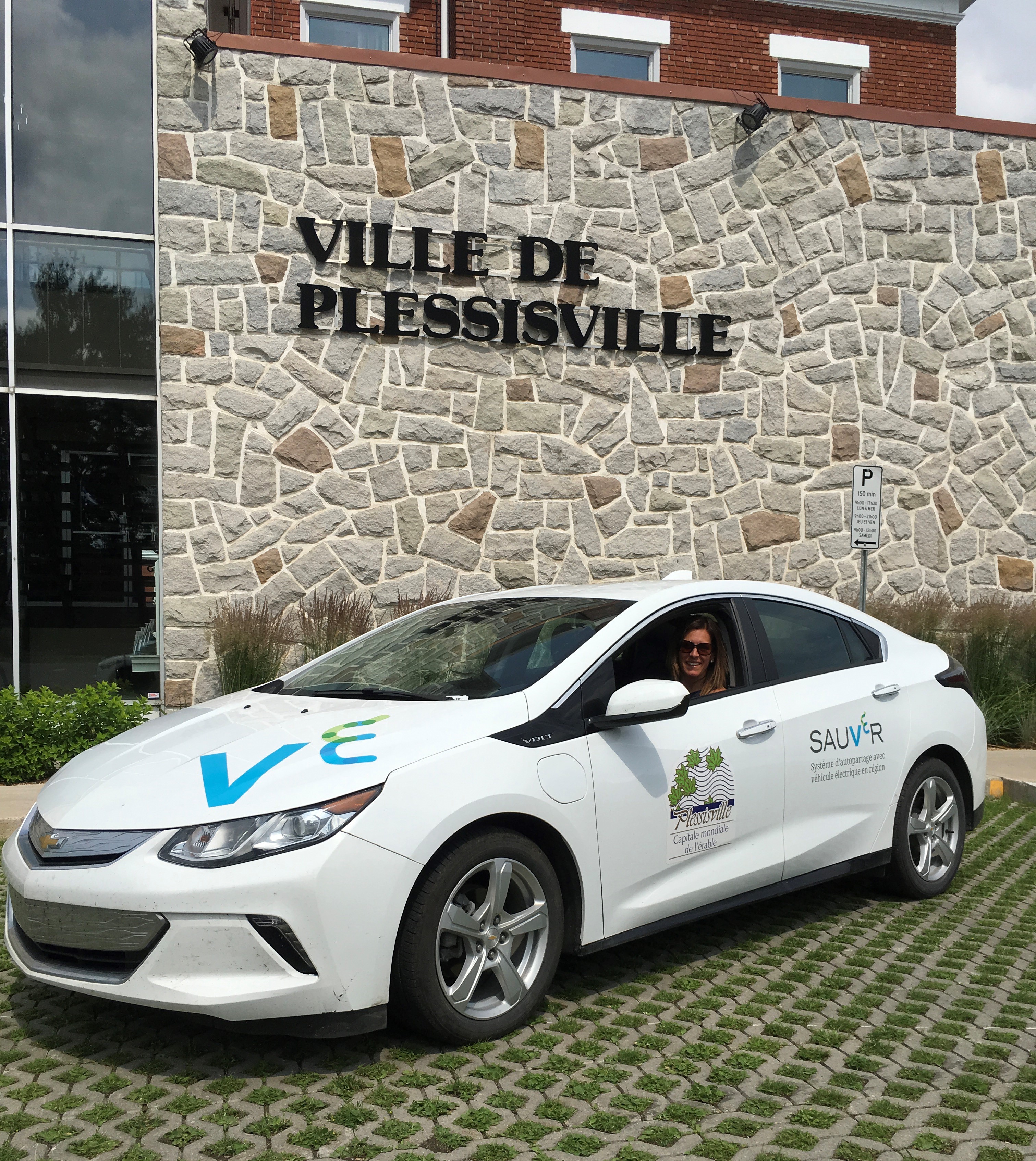 A Plessisville resident smiling, sitting in one of the new electric vehicles