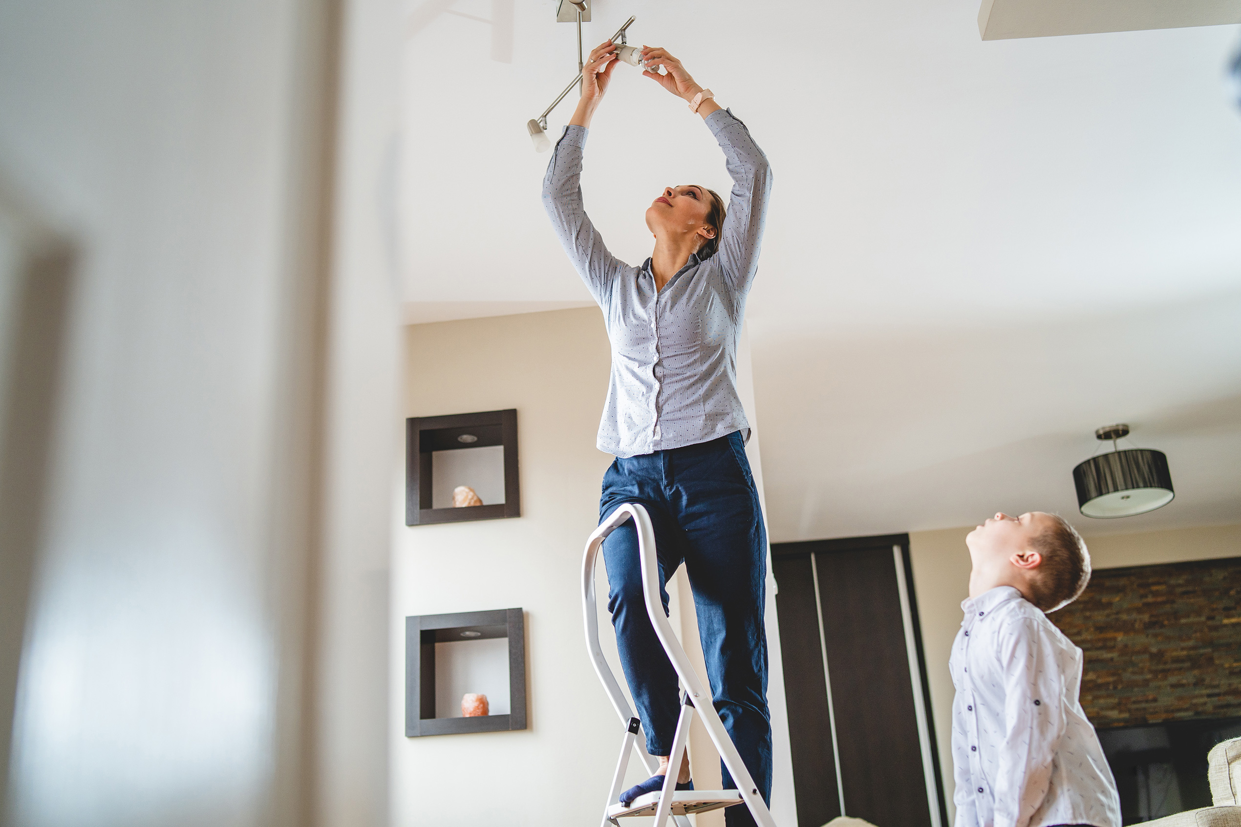 Little boy helping mother to change a lightbulb