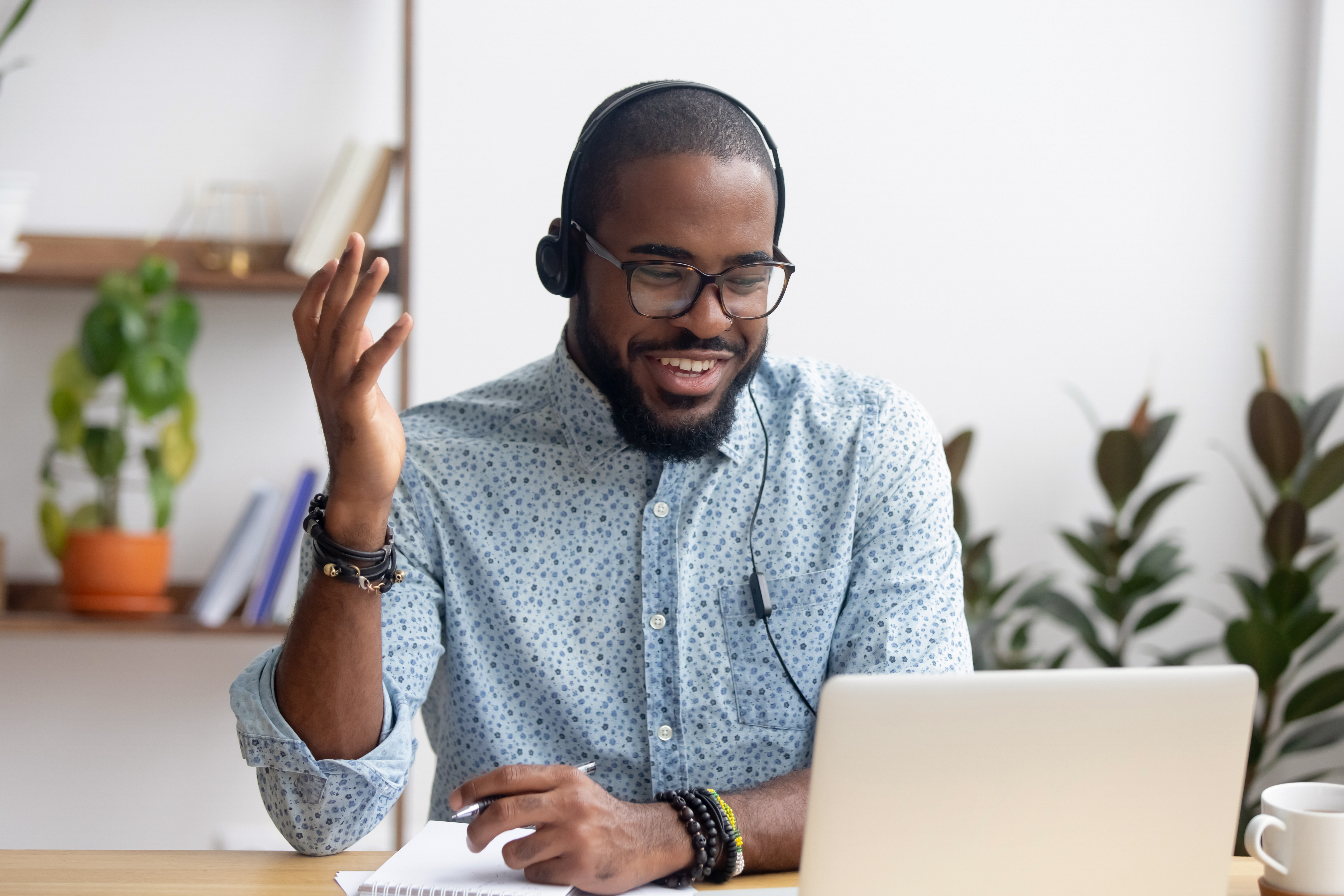 Smiling African American employee in headphones using laptop 