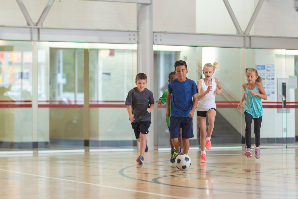 Kids playing soccer in a community gymnasium