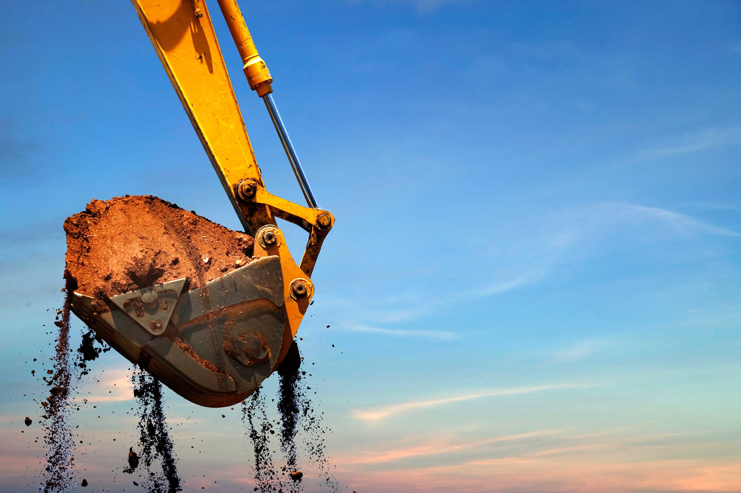 Backhoe being operated at sunset.