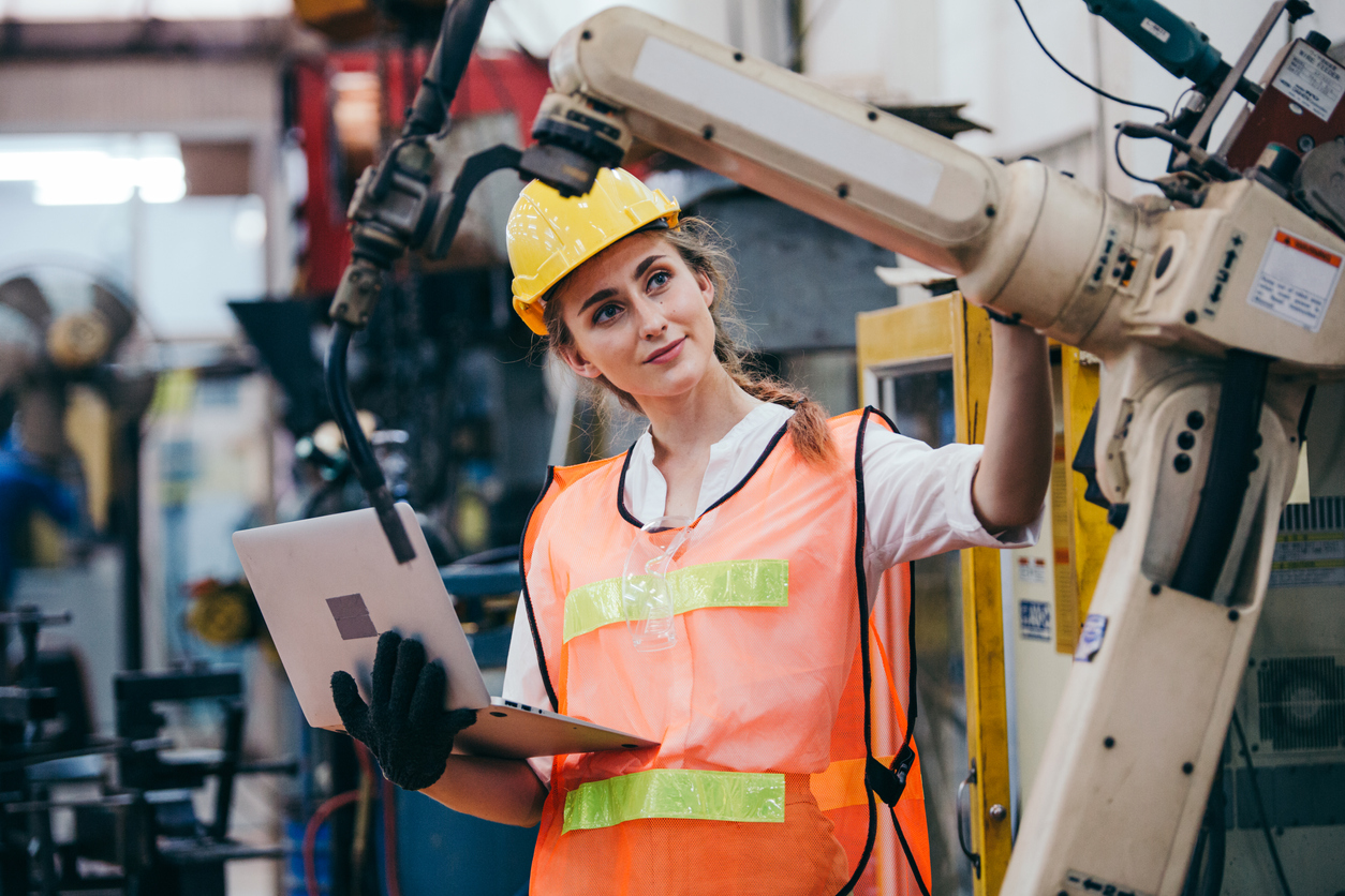 An engineer wearing a hard hat and safety vest inspects the machines.