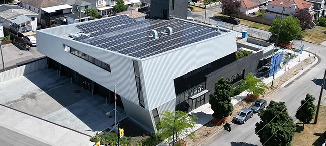 Aerial view of a modern building with rooftop solar panels in an urban environment   