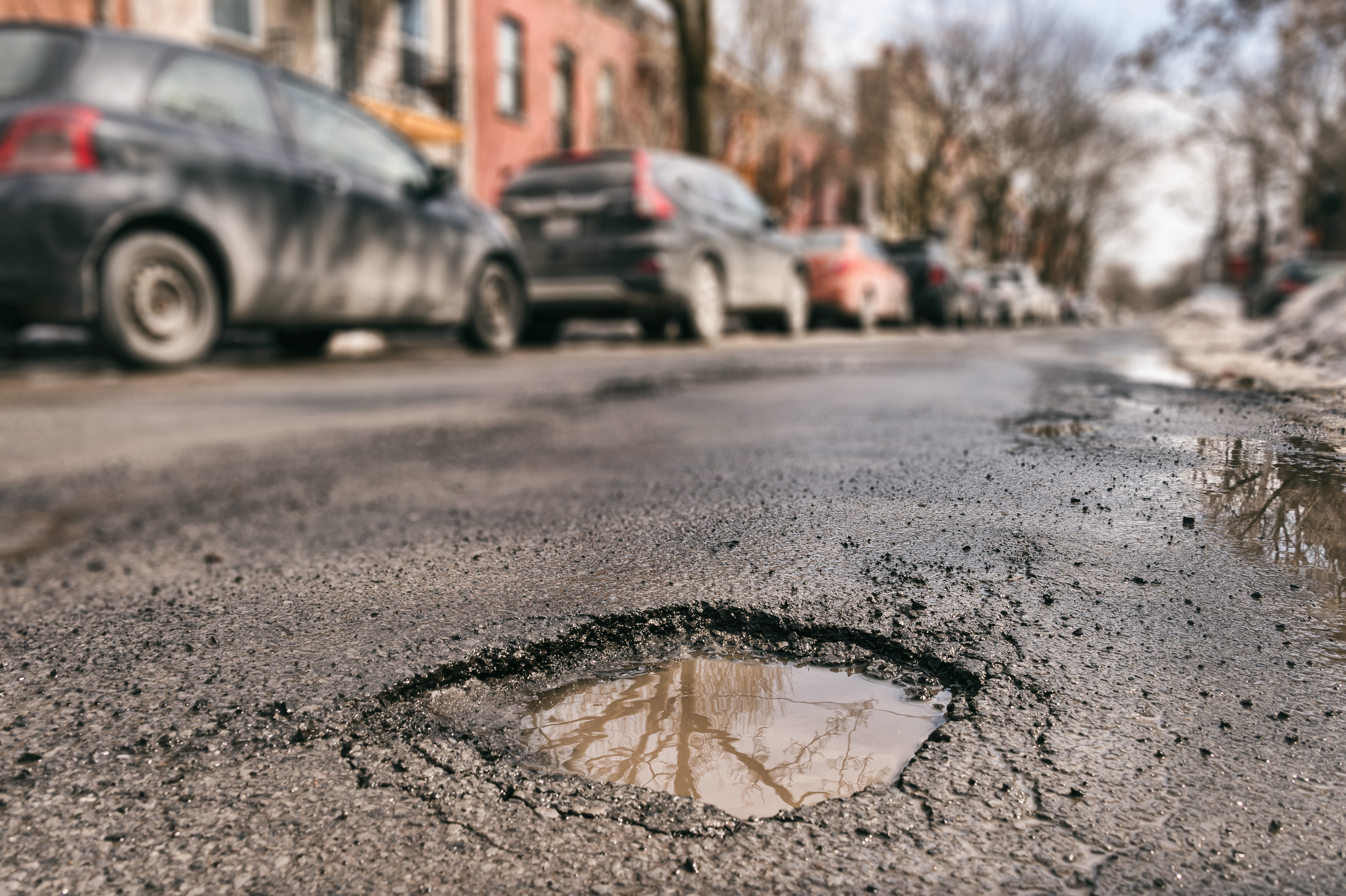 Close-up of a pothole filled partly with water on a suburban street.