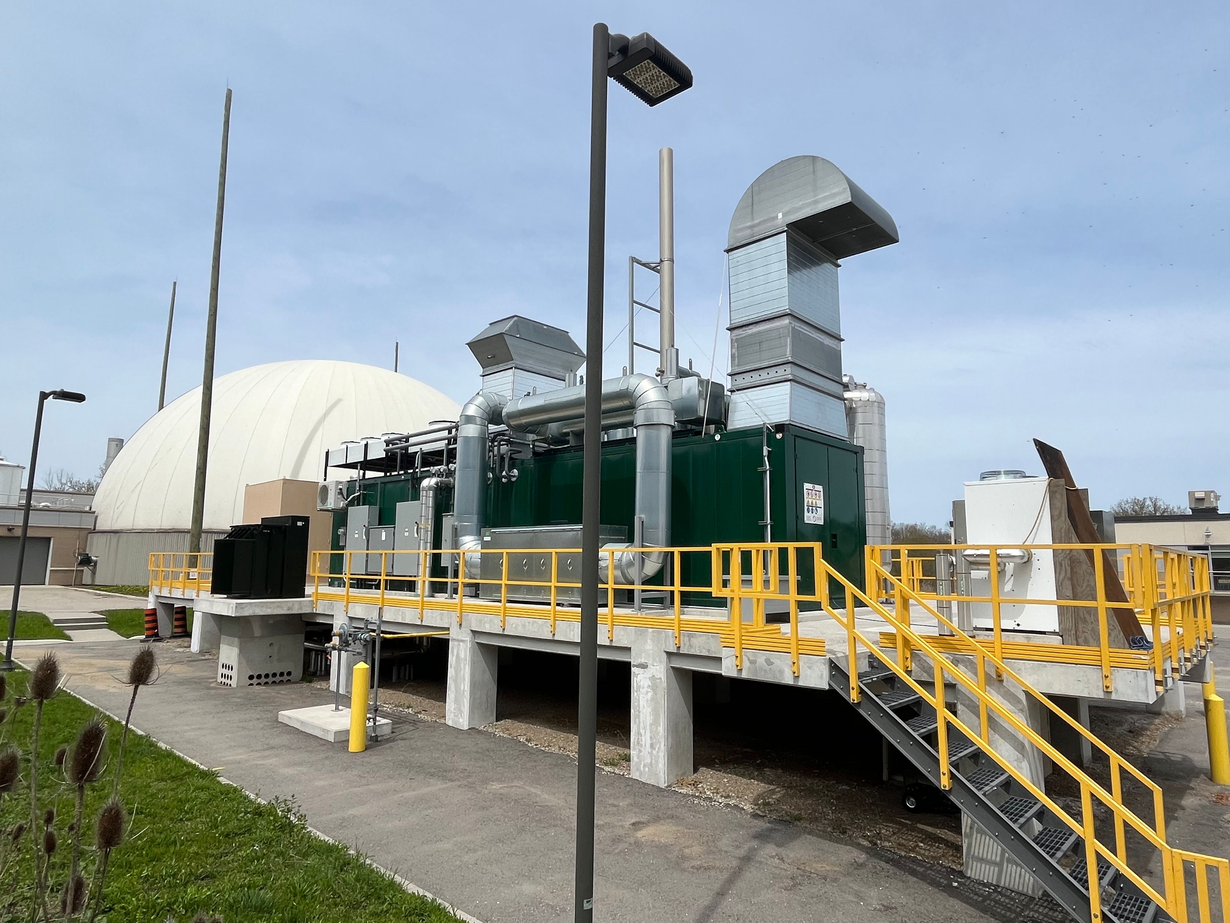 Outdoor view of a facility’s mechanical systems, including metal ducting, on an elevated platform with yellow railings.