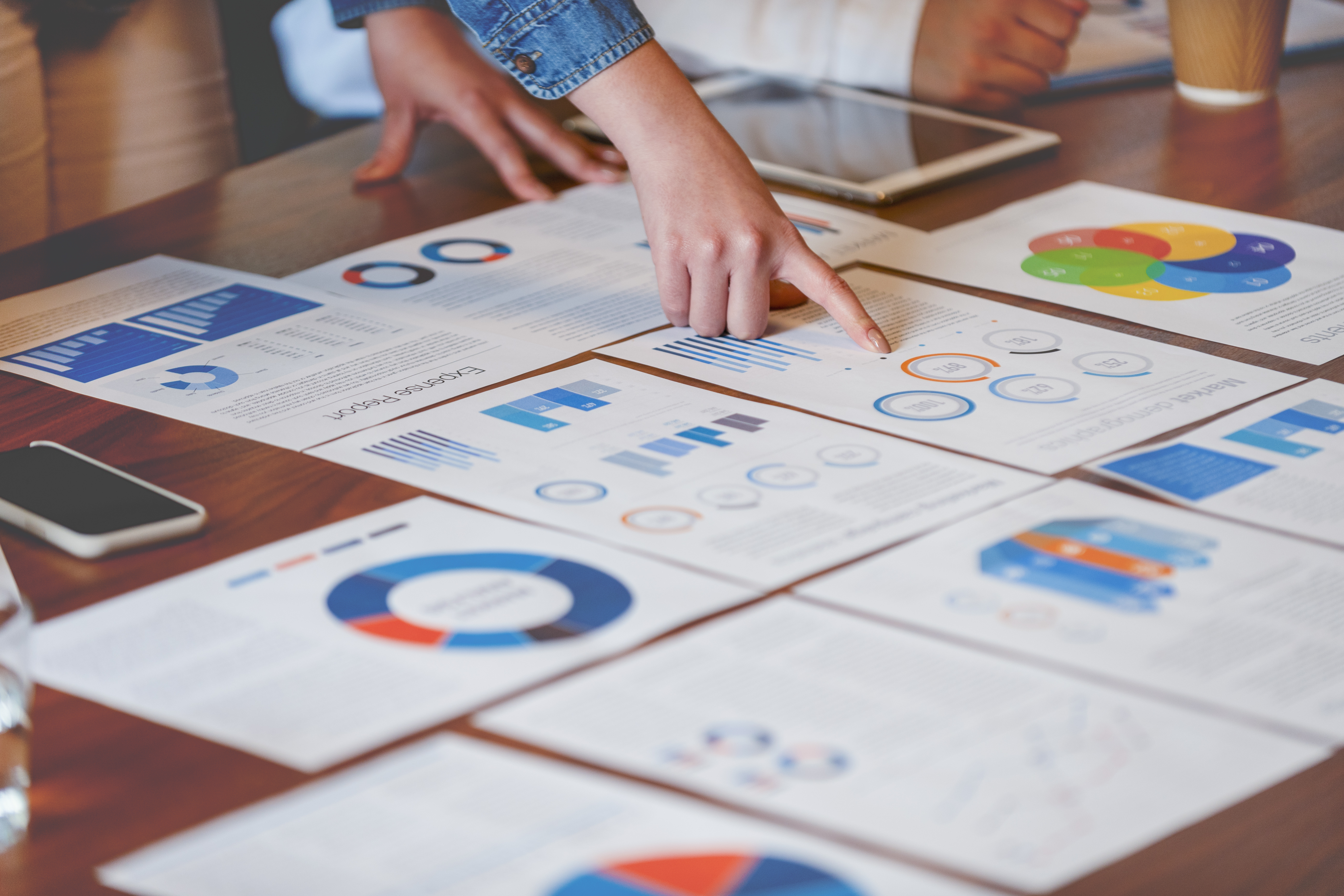 Close-up of hands analyzing printed reports with charts, graphs, and data visualizations, representing climate risk assessment and data-driven decision-making.