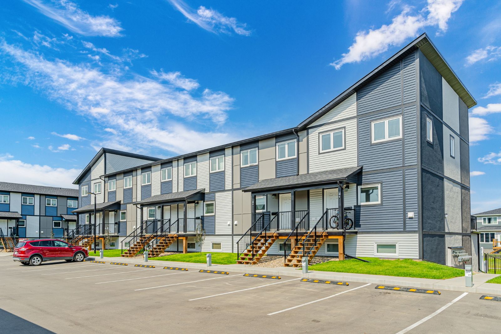A ground-level views of a row of townhouses at the Aspen Heights complex, with a parking lot out front