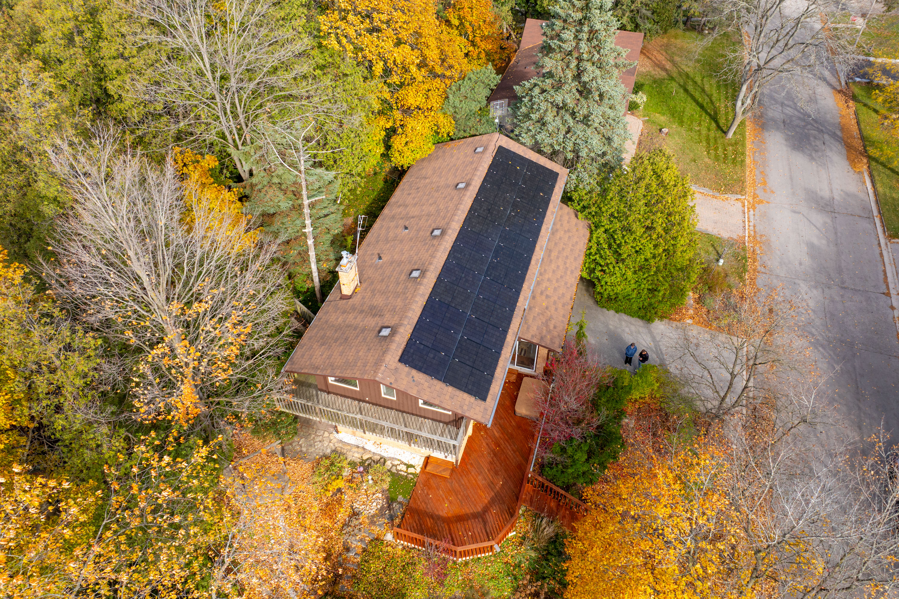 Aerial view of home in wooded area with new solar panels on its roof. 