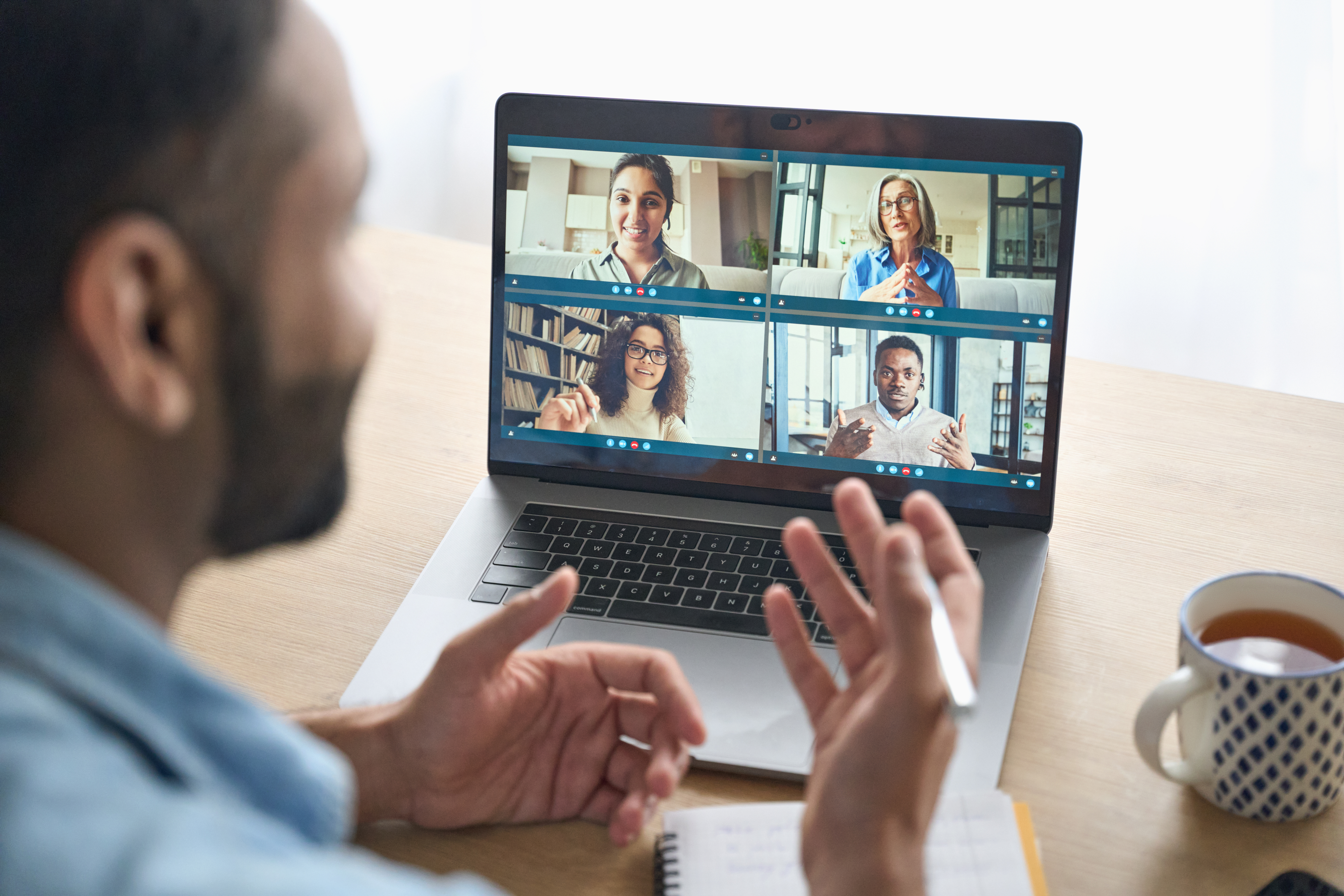A man participating in a virtual meeting with five diverse individuals, representing remote collaboration and knowledge sharing. 