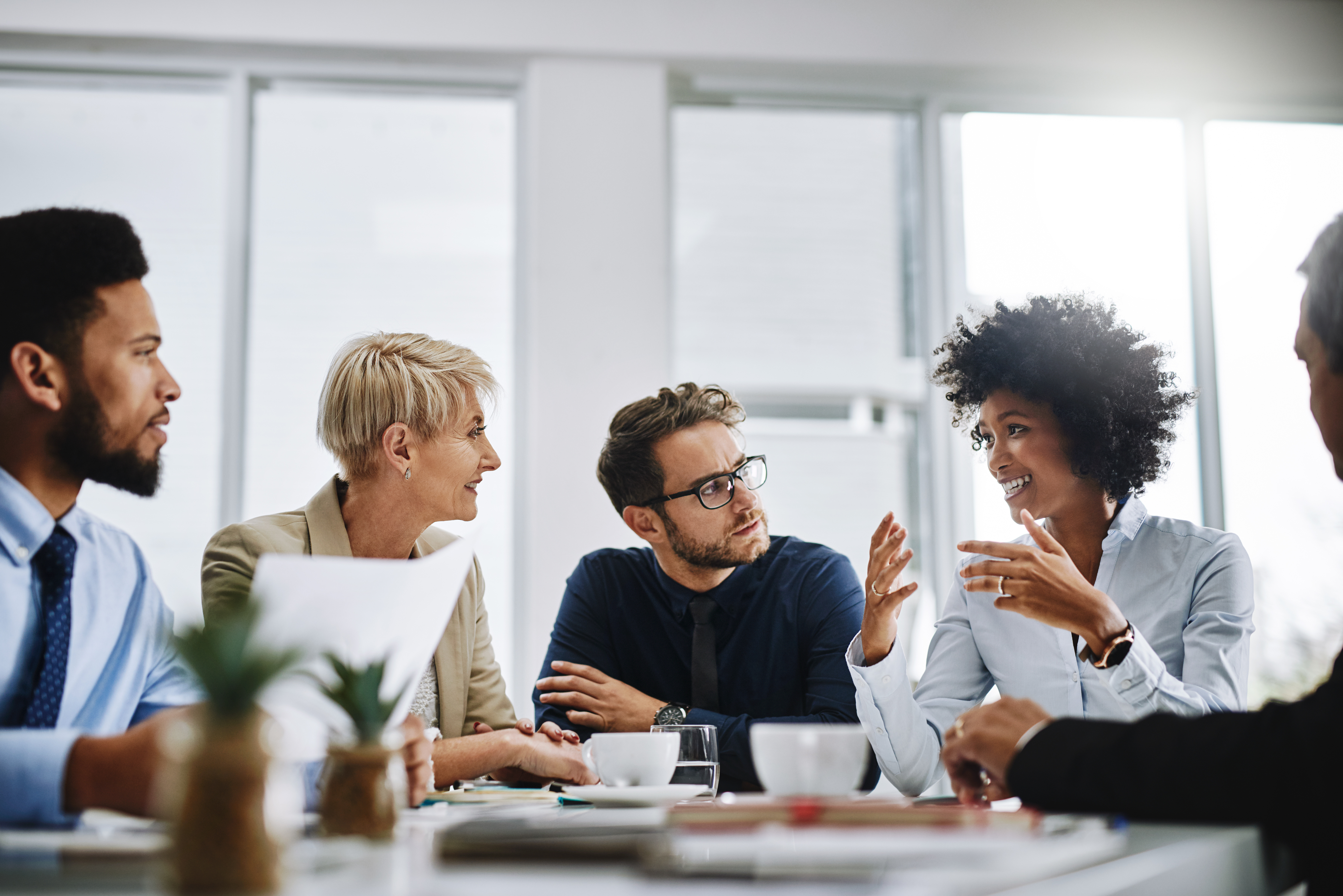 Un groupe diversifié de professionnels assis dans une salle de réunion, discutant d’idées et collaborant autour d’une table.