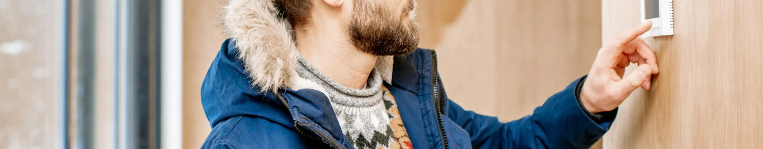 man adjusts thermostat