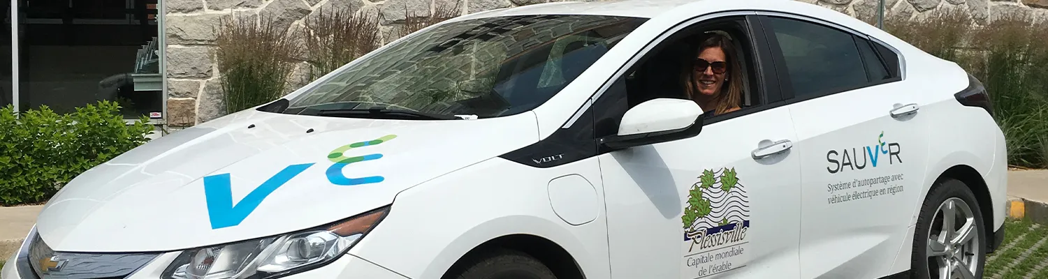 A Plessisville resident smiling, sitting in one of the new electric vehicles