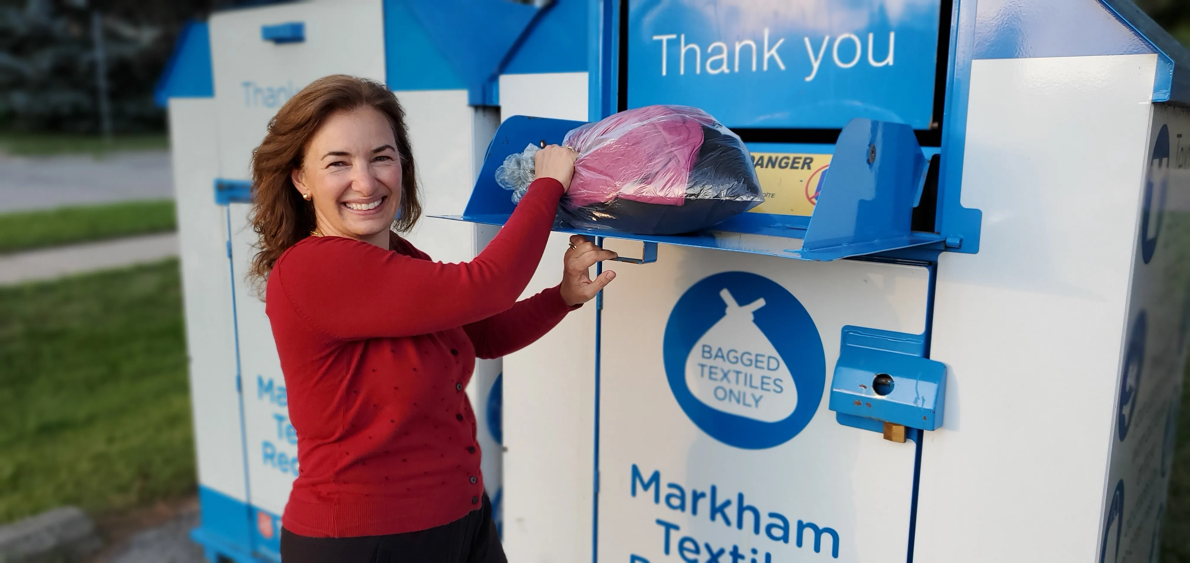 A resident opening the bin and donating a large bag of clothing.