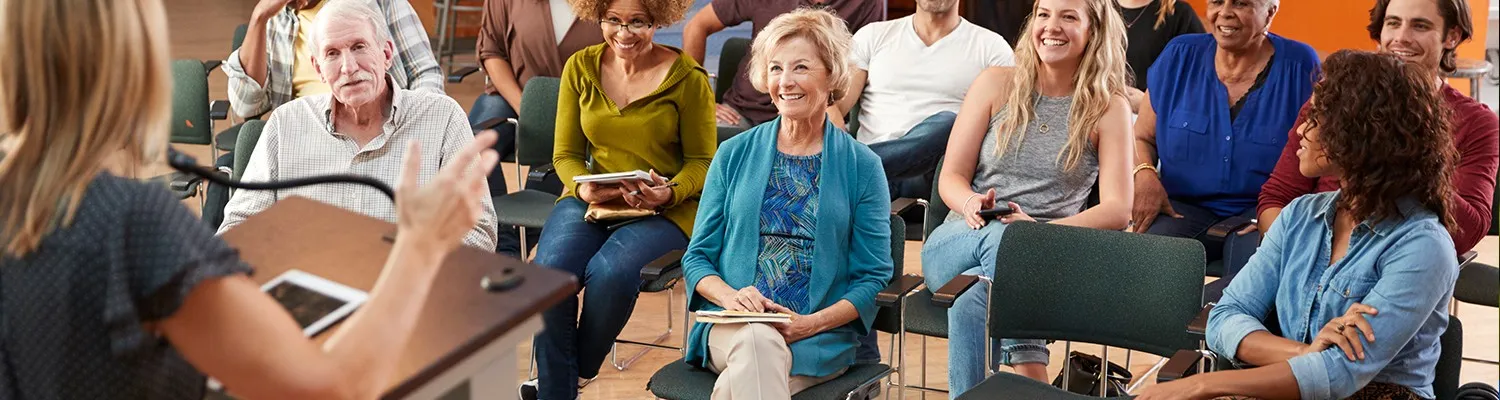 Group of people attending a meeting, sitting and listening to a speaker.