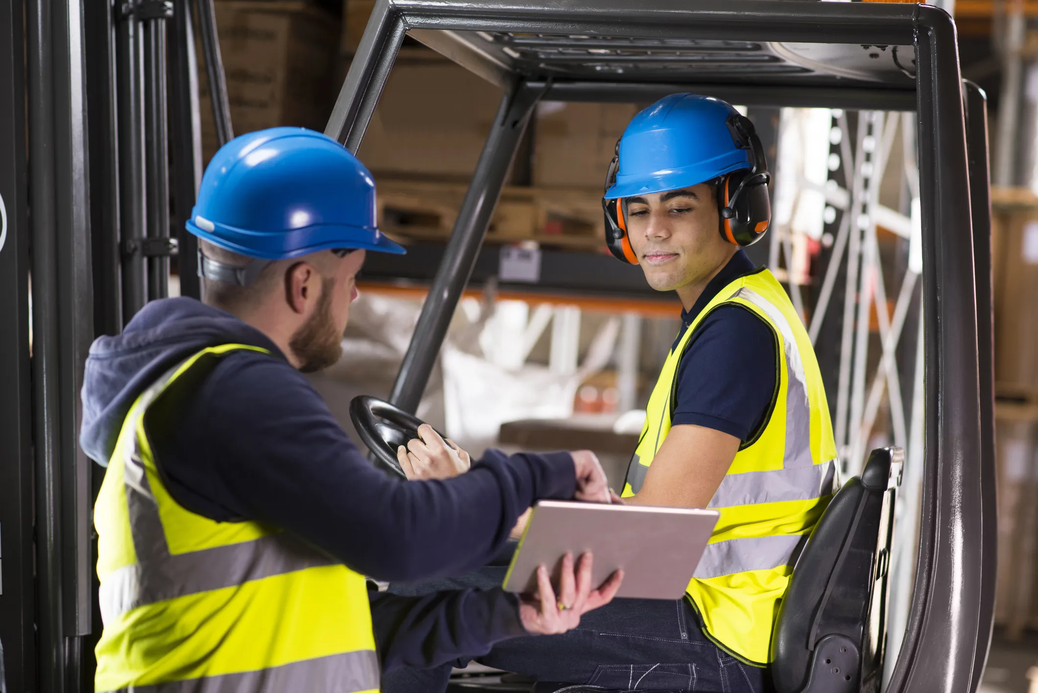 Warehouse supervisor teaches young new hire how to operate forklift. 