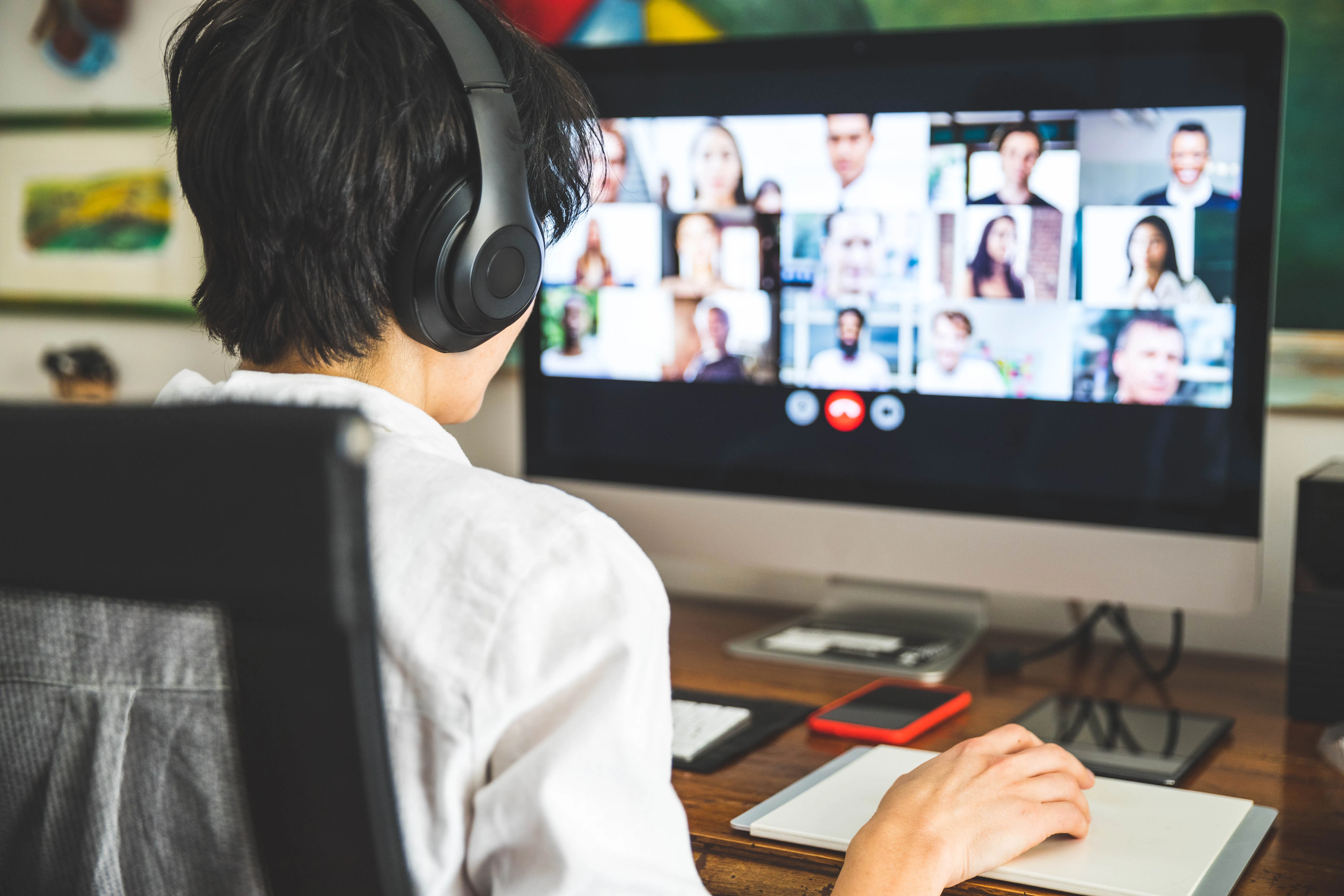 Business woman participating in a video call with several of her colleagues' faces onscreen.