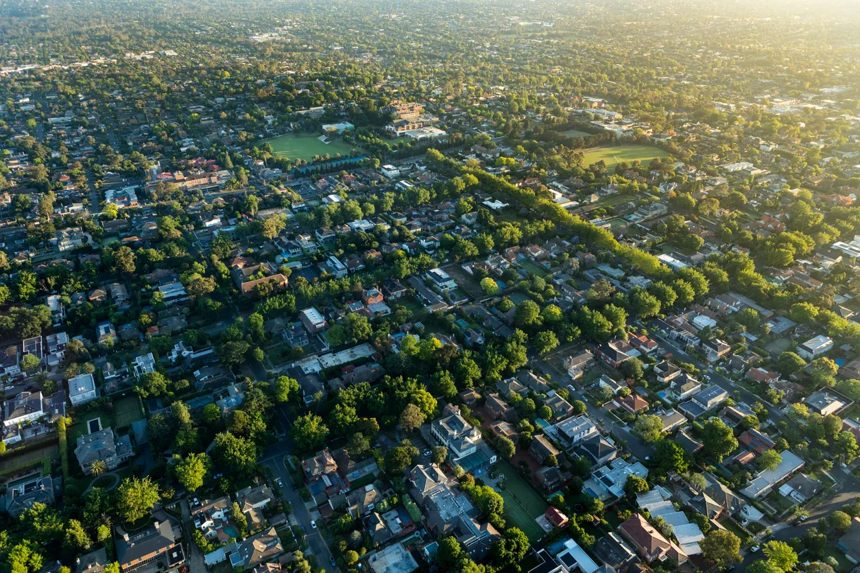 Vue aérienne d'un quartier entouré d'arbres au lever du soleil.