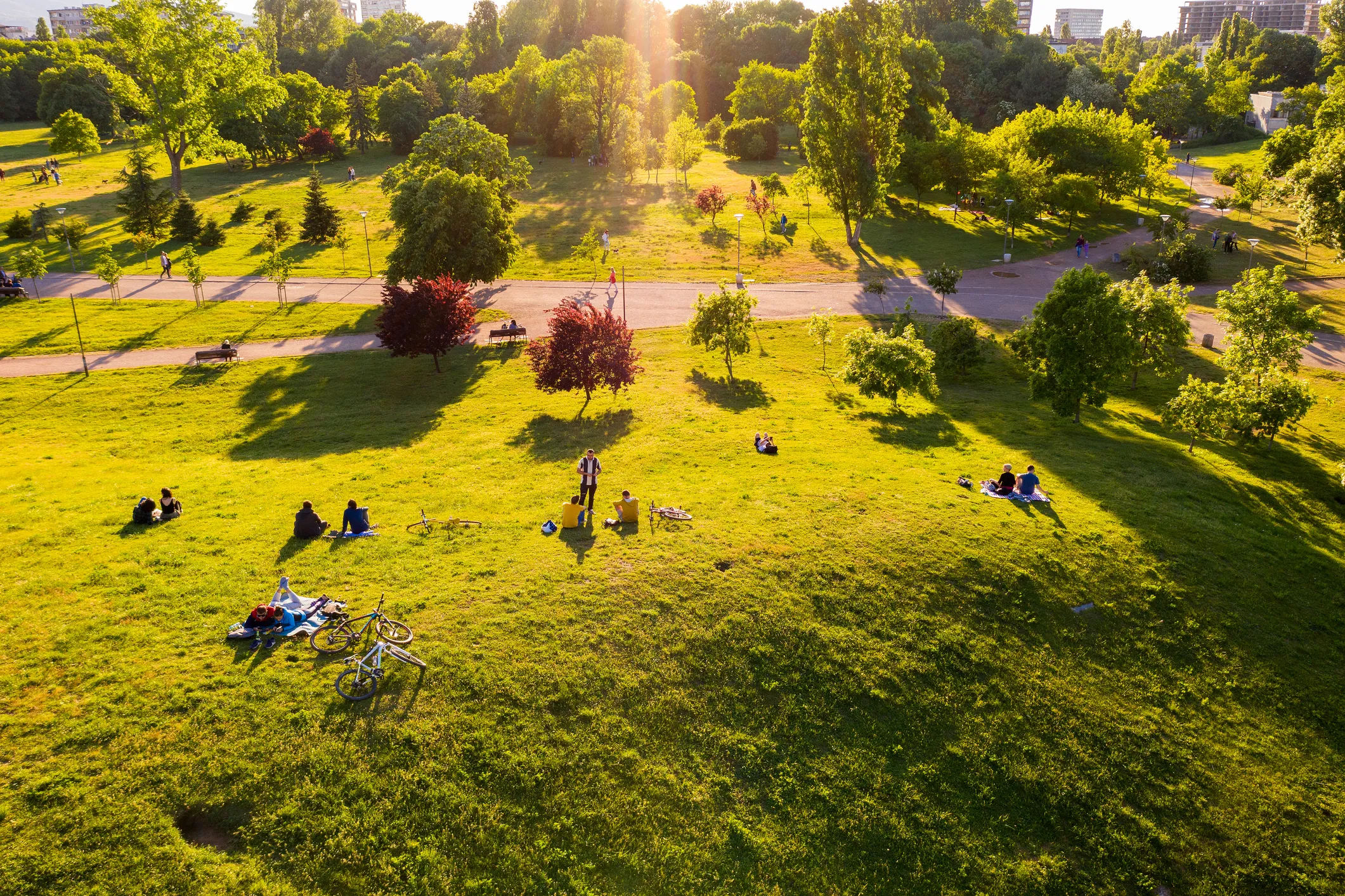 Vue aérienne d'un parc vert avec des personnes qui relaxent sous la lumière chaude du soleil.