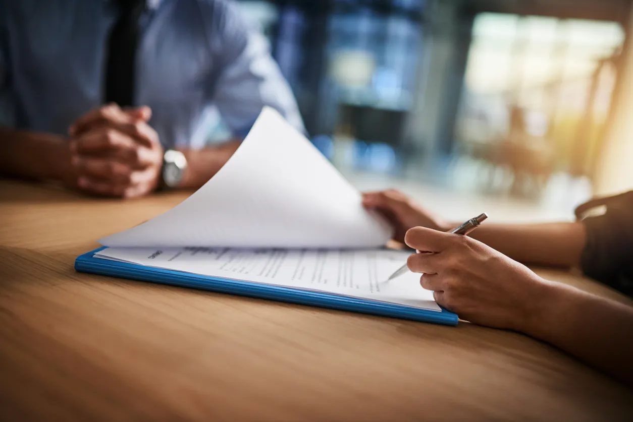 close up two people completing paperwork at a desk