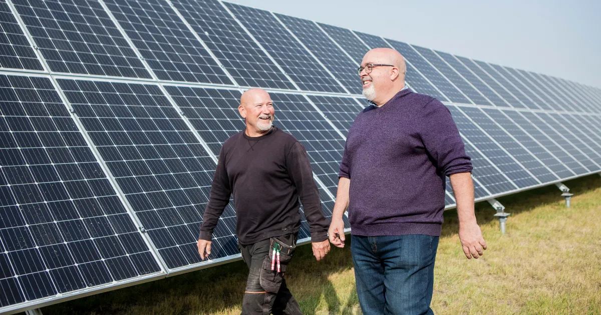 Two men walking in front of solar panels in Alberta